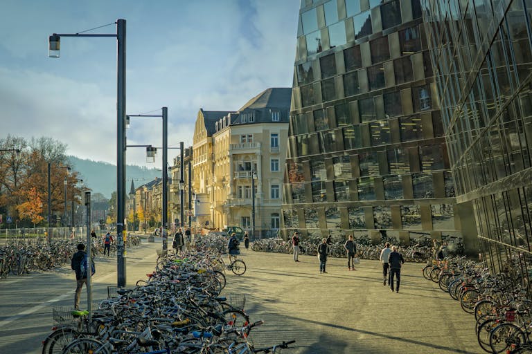 A vibrant city street bustling with bicycles and pedestrians under a sunny sky near modern architecture.