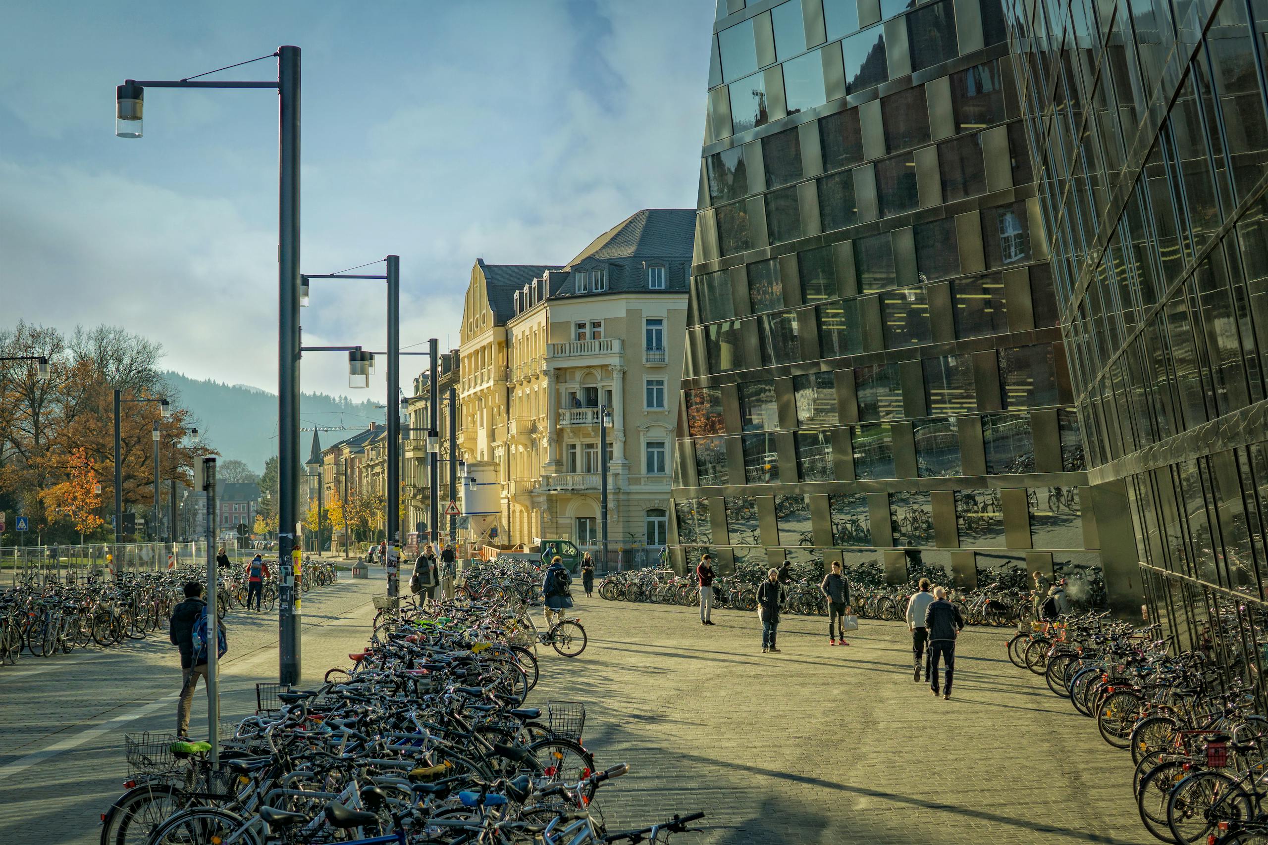 A vibrant city street bustling with bicycles and pedestrians under a sunny sky near modern architecture.