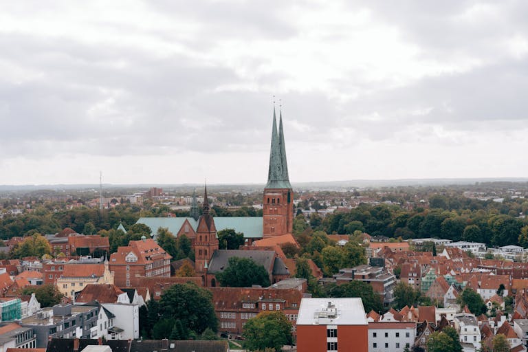 Breathtaking aerial view of Lübeck's skyline with historic church spires and lush greenery.