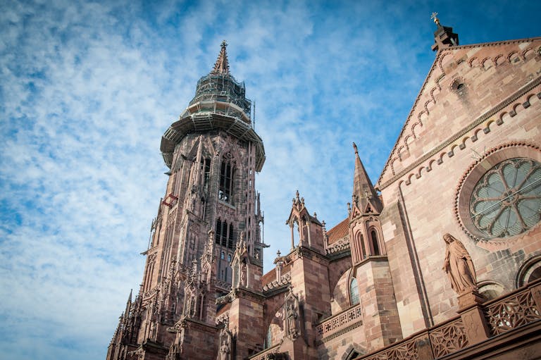 Gothic cathedral facade and tower under a blue sky in Freiburg, Germany.
