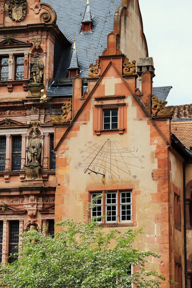 Sundial on a historic building facade in Heidelberg Castle, showcasing classic German architecture.